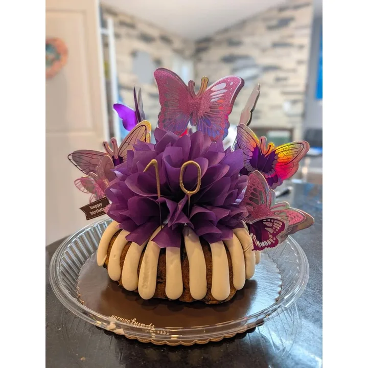 A purple-frosted birthday cake decorated with butterflies and a gold number ten.